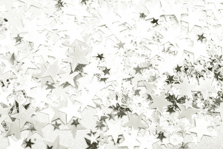 Shiny silver star confetti creating festive background texture.