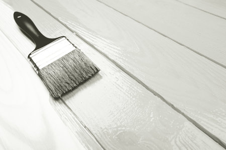 Paintbrush applying white paint to wooden boards.の写真素材