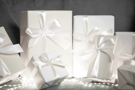White gift boxes with silk ribbons and festive lights.の写真素材