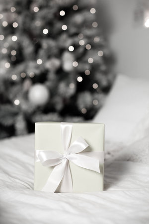 Gift box on bed with christmas tree bokeh.の写真素材