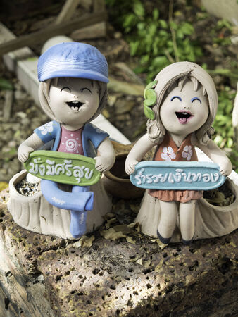 Happy boy and girl doll pottery with 2 Thai word   Boy   Have a healthy rich, Girl   be rich の写真素材