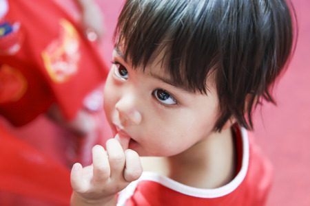 Bangkok, Thailand - Jan 23, 2012   Asian child sucking  thumb in dress red clothのeditorial素材
