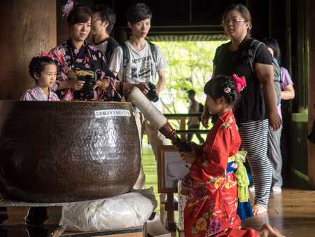 Kyoto,Japan - June 28, 2014 : Unidentified  kimono girl hit a bell for a luck. Kiyomizu temple and is one of the most visited historic area in Japan.のeditorial素材