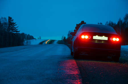 black car at night near the curb in the rainの写真素材