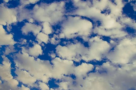 cumulus clouds float across the blue skyの写真素材