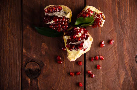 juicy pomegranate on wooden boards.cut into pieces of ripe pomegranate. the pomegranate is ripe. ripe pomegranate seeds. fresh juicy leavesの写真素材