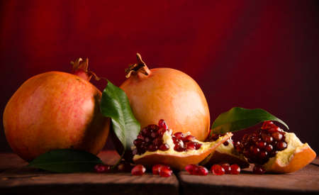 juicy pomegranate on wooden boards.cut into pieces of ripe pomegranate. the pomegranate is ripe. ripe pomegranate seeds. fresh juicy leavesの写真素材