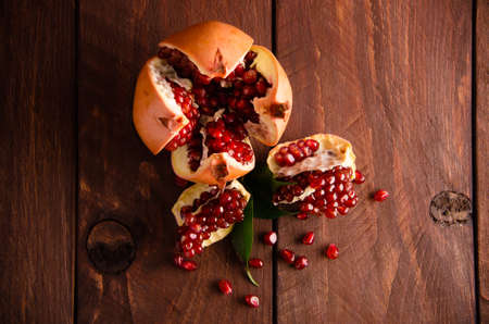 juicy pomegranate on wooden boards.cut into pieces of ripe pomegranate. the pomegranate is ripe. ripe pomegranate seeds. fresh juicy leavesの写真素材