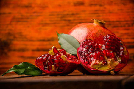 ripe pomegranate seeds. fresh juicy leaves. juicy pomegranate on wooden boards.cut into pieces of ripe pomegranate. the pomegranate is ripe.の写真素材
