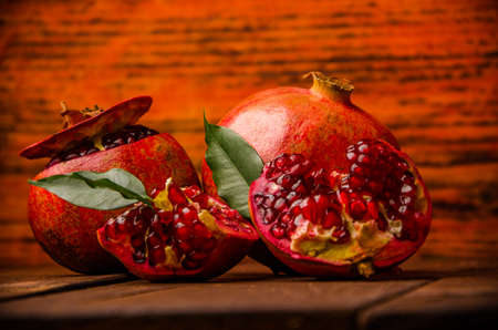 ripe pomegranate seeds. fresh juicy leaves. juicy pomegranate on wooden boards.cut into pieces of ripe pomegranate. the pomegranate is ripe.の写真素材