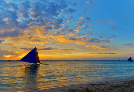 Sailboat against a orange sunset.の写真素材