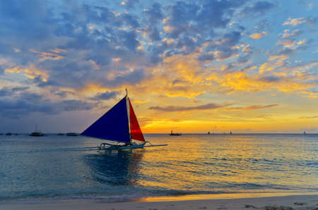 Sailboat against a orange sunset.の写真素材