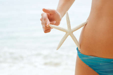 Woman with starfish on the beach.の写真素材