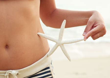 Woman with starfish on the beach.の写真素材