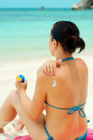 Woman applying sun lotion on the beach.の写真素材