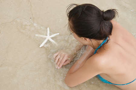 Young woman with starfish on the beach.の写真素材