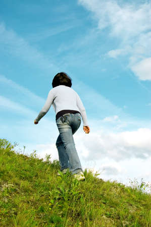 Woman rises on a green hill.の写真素材