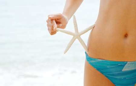Woman with starfish on the beach.の写真素材
