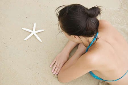 Young woman with starfish on the beach.の写真素材