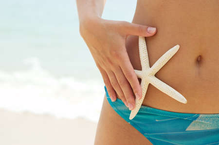 Young woman with starfish on the beach.の写真素材