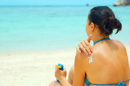 Woman applying sun lotion on the beach.の写真素材