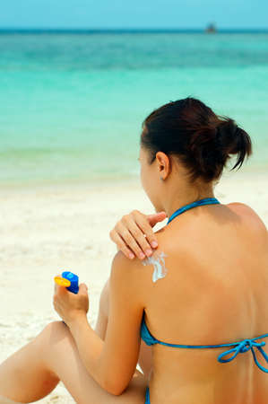 Woman applying sun lotion on the beach の写真素材