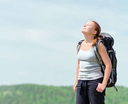 Woman with backpack on green hill.