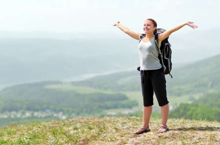Woman with backpack on green hill.の写真素材
