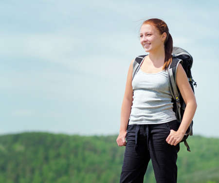 Woman with backpack on green hill.の写真素材