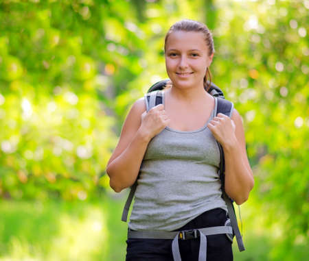 Young woman with backpack in a woods. Hiking at summertime.の写真素材