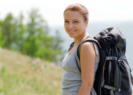 Woman with backpack on green hill.の写真素材