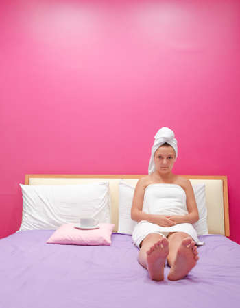 Young woman on a bed in bedroom.の写真素材