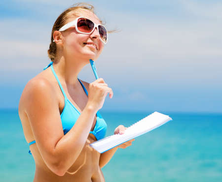 Young woman with notebook on a beach.の写真素材