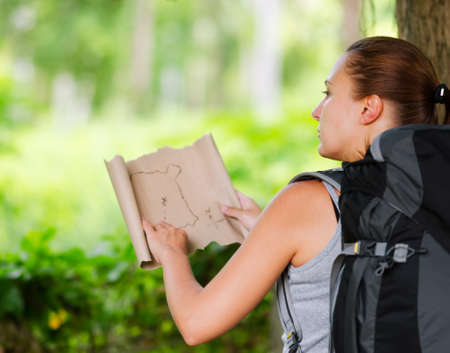 Young woman with backpack in a woods. Hiking at summertime.の写真素材