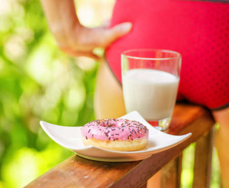 Young woman sitting on terrace with milk and donut.の写真素材