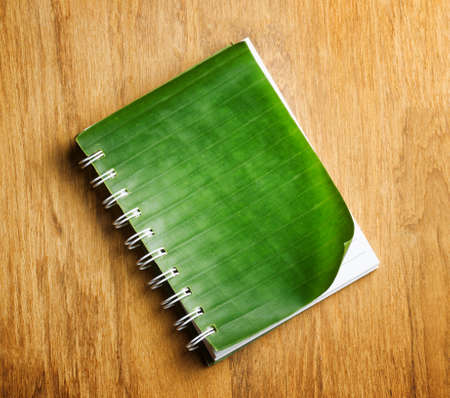 Notepad with cover of leaf lies on wooden board.の写真素材