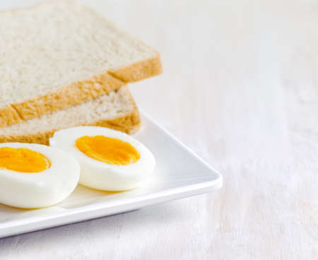 Boiled egg and toasts on white plate.の写真素材