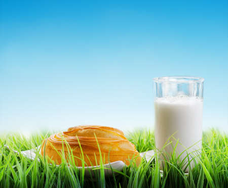 Fresh cinnamon bun and glass of milk on sky backgroundの写真素材