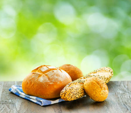 Fresh bread and checkered napkin on  wooden table on rural background.