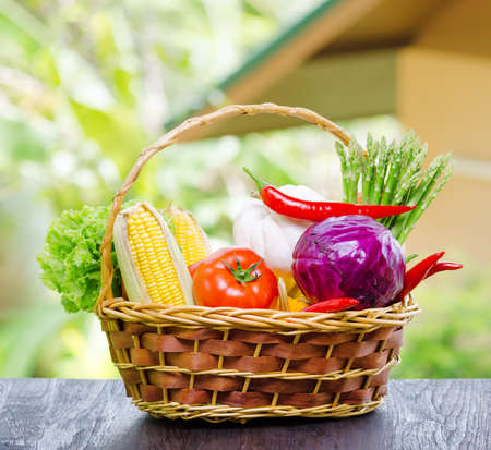Fresh vegetables in the basket on wooden table.の写真素材