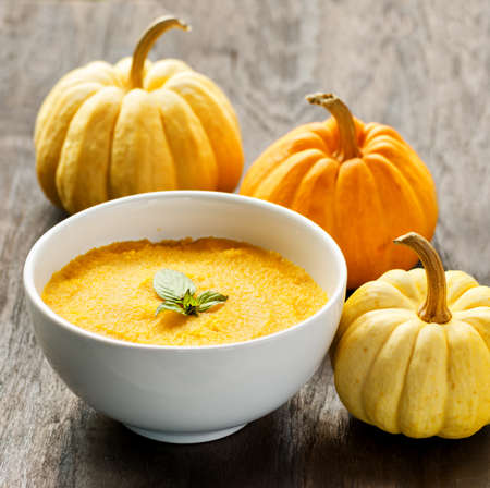 Pumpkin porridge and pumpkins on black wooden table の写真素材