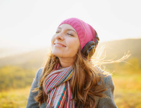 Young woman enjoying a music in the fall season. Autumn outdoor portrait.