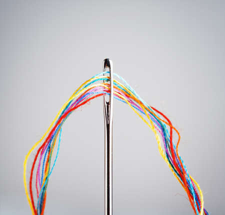 Several colourful threads in a needle.