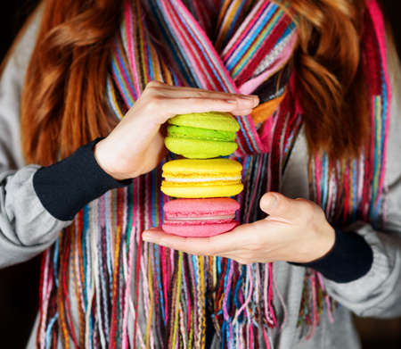 Young woman holding the french pastry macaron in cafe の写真素材