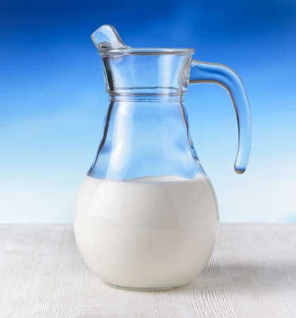 Jug of milk on sky background. Half full pitcher.の写真素材