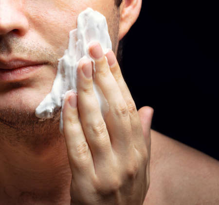 Young man applying a shaving foam. Skin protection.