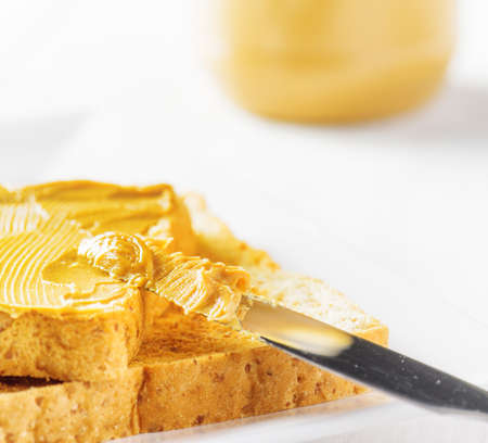Jar of peanut butter and toasts on white table.の写真素材