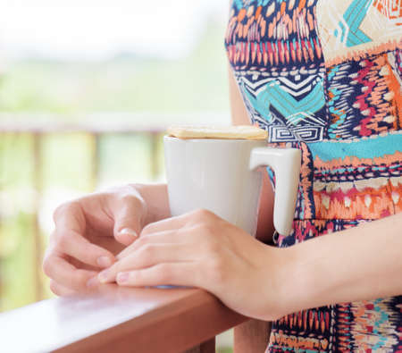 Young woman enjoying a mug of beverage. Outdoor portrait. Coffee and tea drinking conception.の写真素材