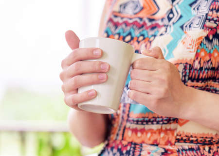 Young woman enjoying a mug of beverage. Outdoor portrait. Coffee and tea drinking conception.の写真素材
