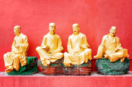 Golden Buddha statues outside the temple of the Ten Thousand Buddhas Monastery with red wall in the background in Hong Kong. Hong Kong is popular tourist destination of Asia.の写真素材